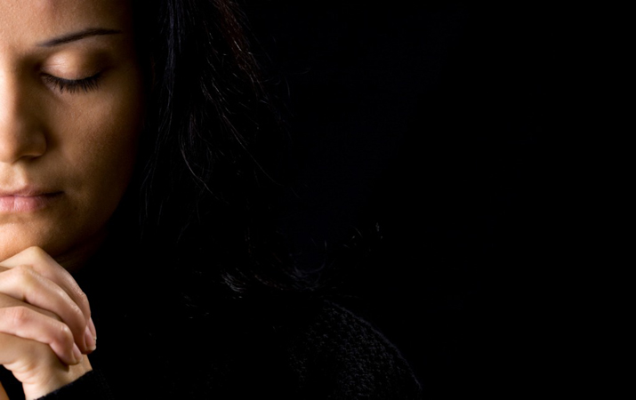 Copy of woman-deep-in-prayer-and-a-black-background-715x450